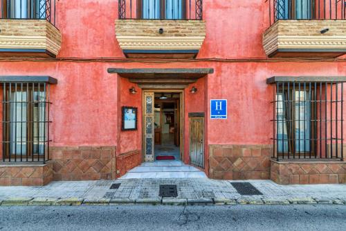 an entrance to a red building with a red door at Hotel Pozo Rey in Chipiona