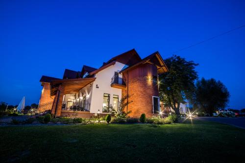 a large brick house with lights on a lawn at Hotel Grodzisko in Grodzisk Mazowiecki