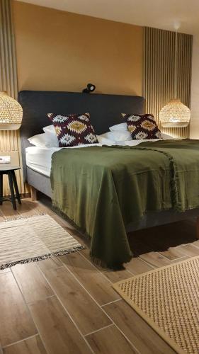 a bed with a green blanket and pillows on it at Prosecco Apartman in Balatonfüred