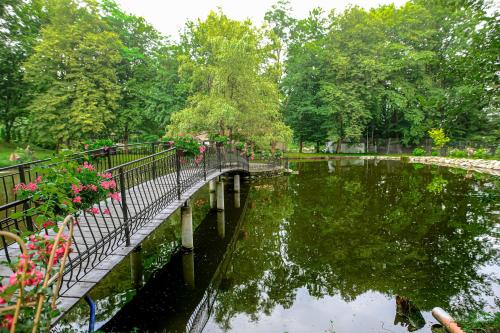 a bridge over a body of water with flowers at Zamek Dubiecko in Dubiecko
