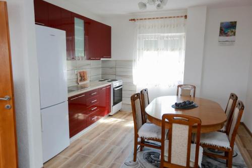 トレビニェにあるApartman Vlačićのキッチン(木製テーブル付)、キッチン(赤いキャビネット付)
