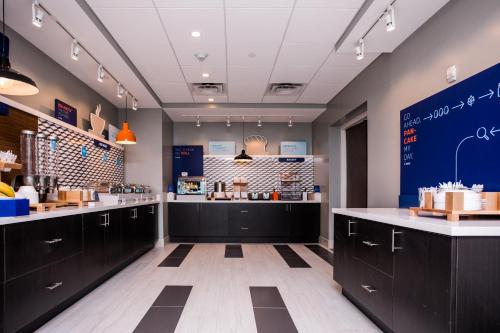 a kitchen with black cabinets and a blue wall at Holiday Inn Express & Suites Rehoboth Beach by IHG in Rehoboth Beach