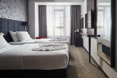 a hotel room with two beds and a television at Hotel Gold in Skopje