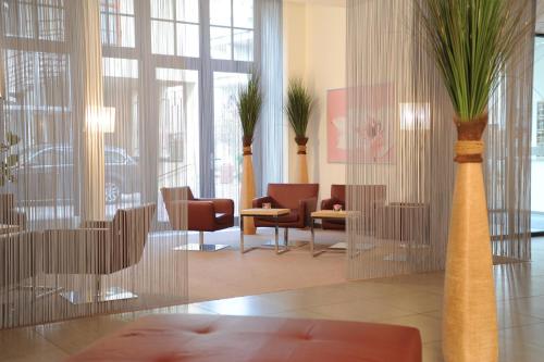 a lobby with chairs and palm trees in vases at Mercure Hotel Erfurt Altstadt in Erfurt