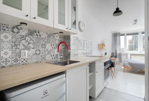 uma cozinha com armários brancos e um lavatório em Bagno Cozy Studio II em Varsóvia