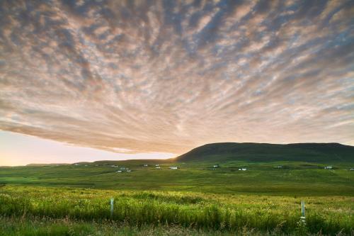 a field with a cloudy sky with a hill in the background at Monkstadt No 7 - Flora's Secret in Portree