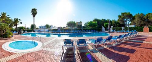 una piscina con sedie blu e un piscina con piscina per il nuoto. di Apartamentos Maribel a Cala Blanca