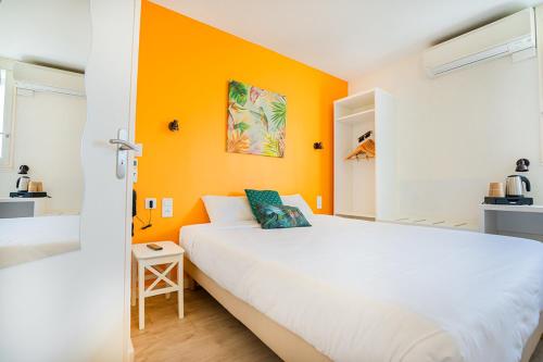 ル・セケストルにあるLogis Hôtel Le Rialtoの白いベッドとオレンジ色の壁が備わるベッドルーム1室が備わります。