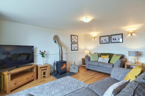a living room with a couch and a tv and a fireplace at Monkstadt No 7 - Flora's Secret in Portree