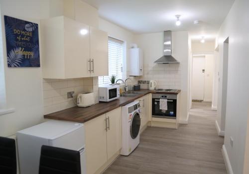 a kitchen with white cabinets and a washer and dryer at Gorgeous ground floor apartment + free parking in Manchester