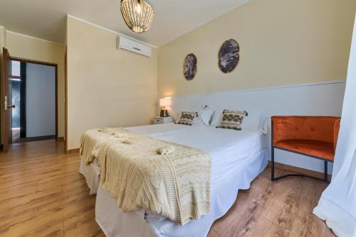 a bedroom with a white bed and a chair at Hotel Pozo Rey in Chipiona