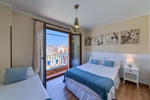 a bedroom with two beds and a balcony at Hotel Pozo Rey in Chipiona