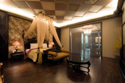 a bedroom with a canopy bed and a table at Harport Motel in Niaosong