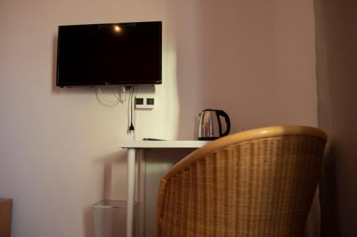 uma televisão pendurada numa parede por cima de uma mesa com uma cadeira em Hotel Ristorante Scirocco em Portopalo