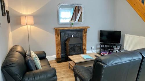 sala de estar con 2 sillas de cuero y chimenea en The Nook, en Embleton