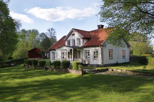 uma casa branca com um telhado vermelho num jardim verde em KvarnDammens Bed & Breakfast em Vetlanda