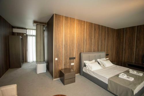 a bedroom with a bed and a wooden wall at Hotel Nobilis Hall in K'obulet'i
