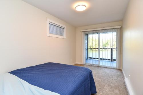 a bedroom with a blue bed and a window at Chateau Riverside in Campbell River