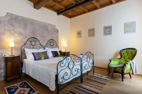 a bedroom with a bed and a green chair at Antica Casa Balsari in Borgo Ticino