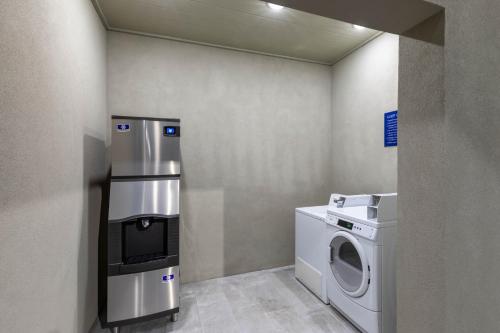 a laundry room with a washing machine and a washer at Days Inn & Suites by Wyndham Downtown/University of Houston in Houston