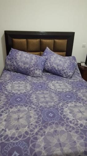 a bed with purple and white sheets and pillows at Résidence Lilia Al Jabal M’diQ in M'diq
