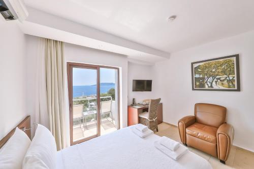 a bedroom with a bed and a chair and a window at Gardenia Hotel in Kas