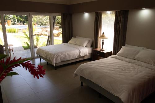 a bedroom with two beds and a large window at Guácima Escondida Hotel Boutique in Guácima