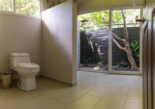 a bathroom with a toilet and a window at Guácima Escondida Hotel Boutique in Guácima