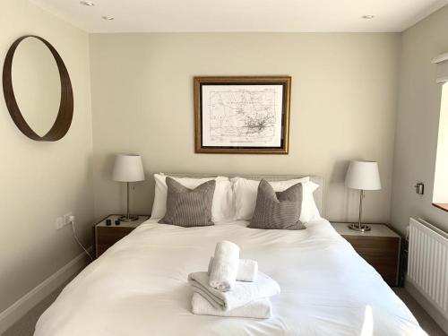 a bedroom with a white bed with towels on it at Brewery Cottage in Abingdon