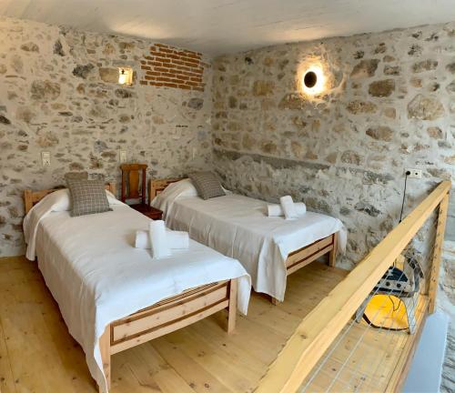 two beds in a room with stone walls at Naiades Residence in Pigi