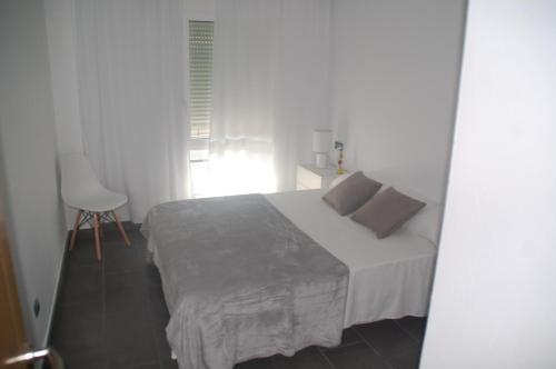 1 dormitorio blanco con 1 cama y 1 silla en Apartament Formentor - Salou, en Salou