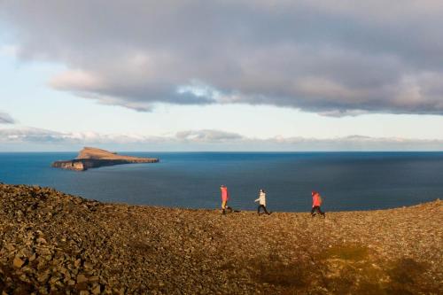 a group of three people walking on a hill near the ocean at Soti Lodge in Fljot