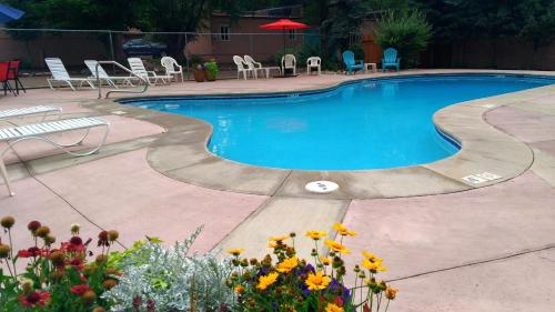 a swimming pool with chairs and flowers in a yard at Buffalo Lodge Bicycle Resort - Amazing access to local trails & the Garden in Colorado Springs
