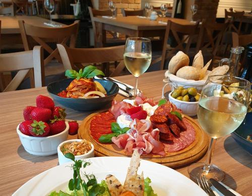 a table with a plate of food and glasses of wine at Willa Pirs in Warsaw