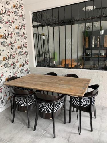 une table en bois entourée de chaises noires dans l'établissement VILLA ROMANA, à Beaumont-sur-Sarthe