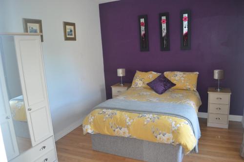 ダウンパトリックにあるSally Gardens Cottageの紫の壁のベッドルーム1室(ベッド1台付)