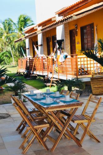 a wooden table and chairs in front of a house at Pousada Ventos do Guajiru-Casa de Kitesurfistas in Itarema