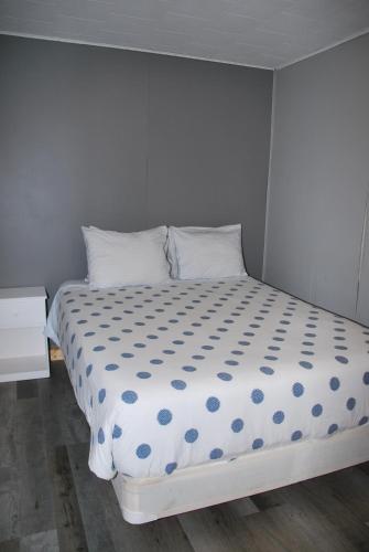 a white bed with blue polka dot sheets and pillows at Jasper Way Inn in Clearwater