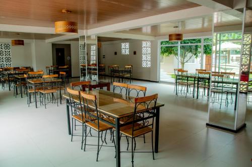 a dining room with tables and chairs and windows at HOTEL CANTINHO DAS FLORES in Guaramiranga