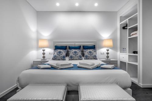 a white bedroom with a large bed with blue pillows at Ilheu 25 Peniche House in Peniche