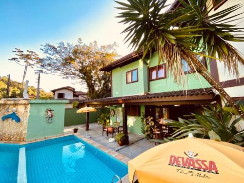 een villa met een zwembad en een huis bij Recanto Verde Praia Hotel Juquehy in Juquei