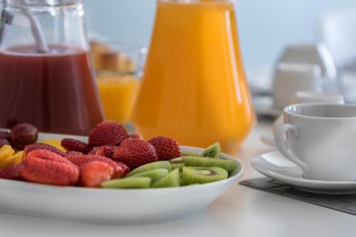 un piatto di frutta su un tavolo con una tazza di succo di Ilheu 25 Peniche House a Peniche