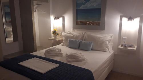 Un dormitorio con una cama blanca con toallas. en Katerina Rooms, en Tinos