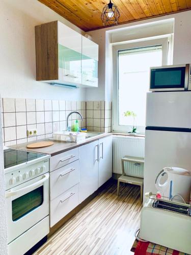 cocina con electrodomésticos blancos y techo de madera en Apartment Apfel, en Mönchengladbach