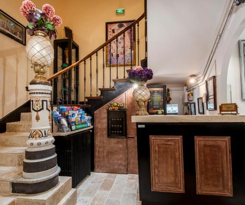 a lobby with a staircase with vases of flowers at Hôtel de Charme Le Provence in Salon-de-Provence