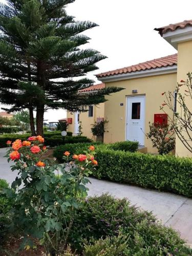 a house with a tree and flowers in a yard at Boutique Hotel Ileas Village in Arkoudi