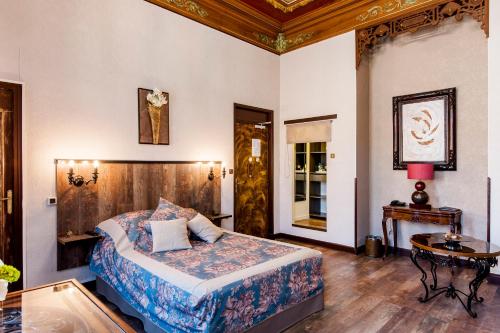 a bedroom with a king sized bed and a table at Hôtel de Charme Le Provence in Salon-de-Provence