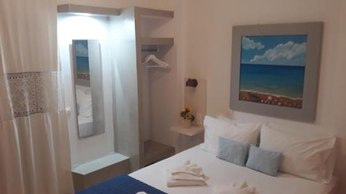 Un dormitorio con una cama blanca y una pintura en la pared en Katerina Rooms, en Tinos