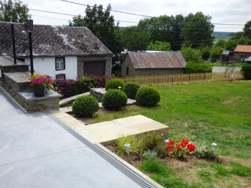a yard with a house and a garden with flowers at La Métairie in Houffalize