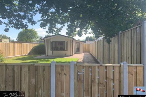 a fence with a tiny house behind a fence at Holiday-Chalet Westenwind 4p. Amsterdam & Beach in Opmeer